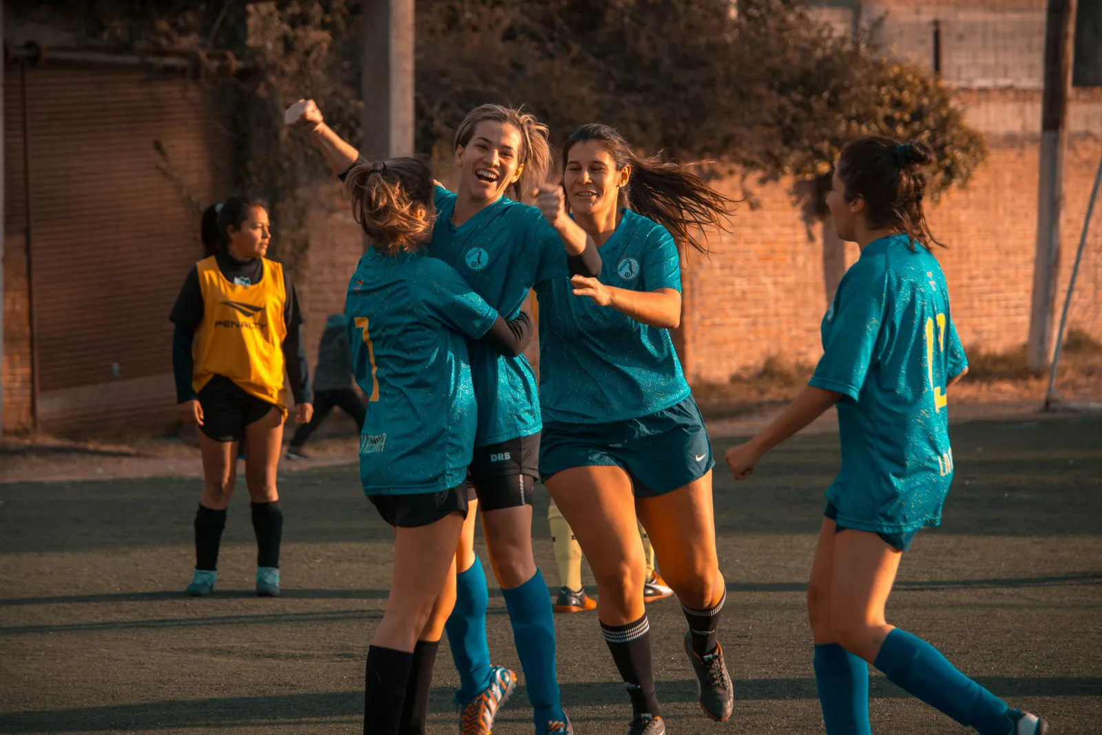Eine Gruppe von Frauenfußballspielern, die sich auf dem Spielfeld umarmen